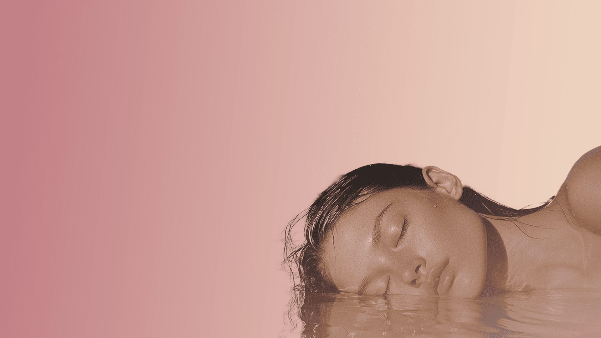 Woman immersed in warm rose-tinted water — GloWellness