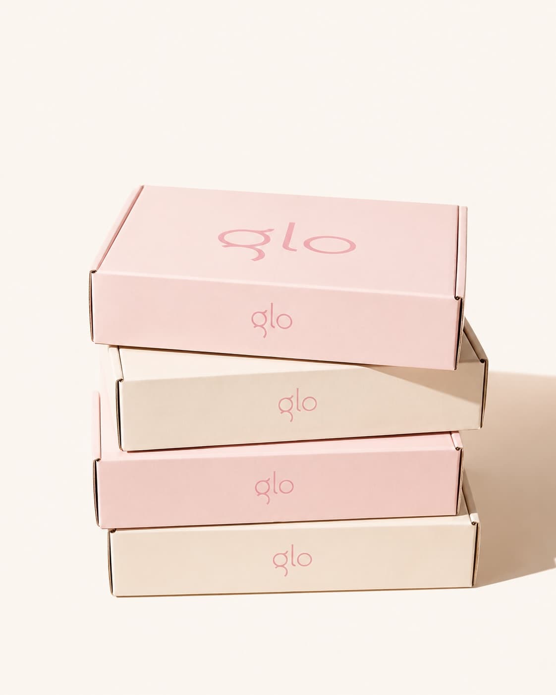 A stack of blush and cream GloWellness shipping boxes.